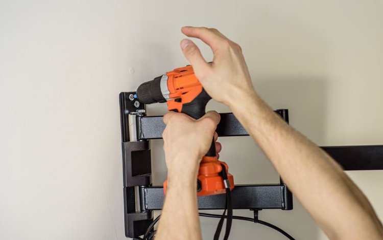 man drills the holes to attchach wall bracket to the wall