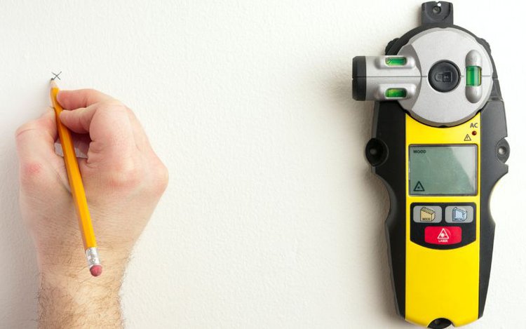 man marking stud inside the wall using a yellow stud finder