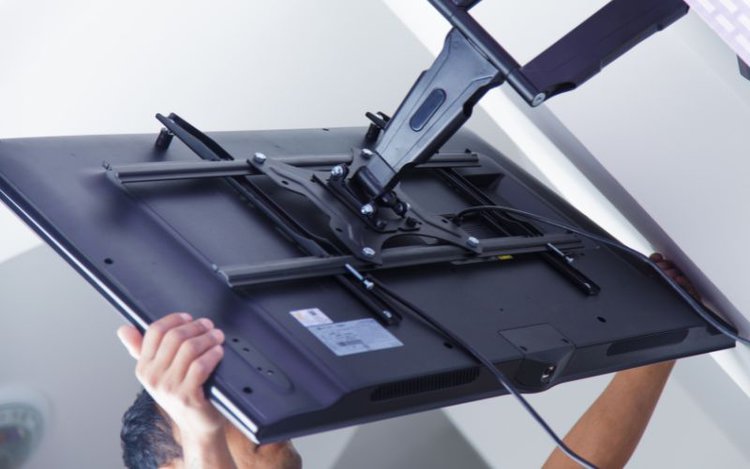 man pulling a TV after mounting it to the wall