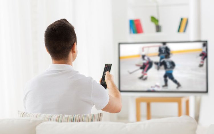 man watching hockey game on TV at home