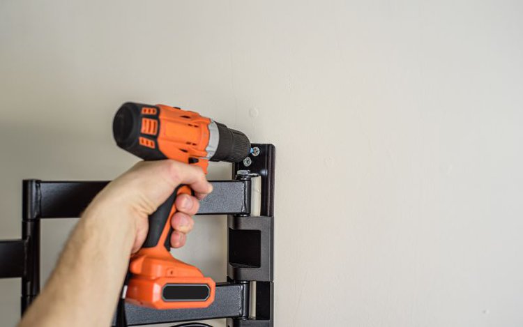 screwing the bolts of TV mount with a power drill