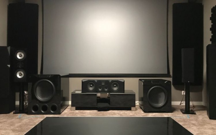 speakers, front projector screen and subwoofers in a home theater setup