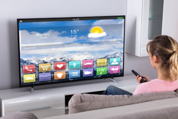 woman holding a remote in front of smart TV