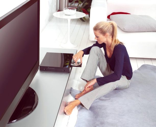 woman putting a DVD into DVD player in her flat