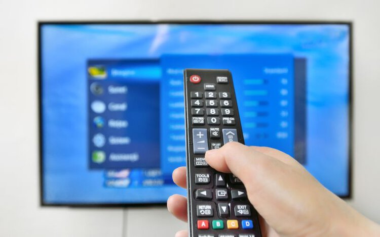 woman using remote control to adjust TV setting