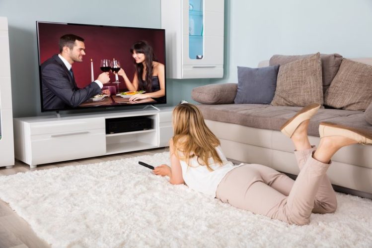 woman watching a movie of couple drinking wine at home