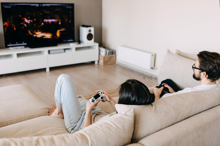 A couple playing game on TV with console controls