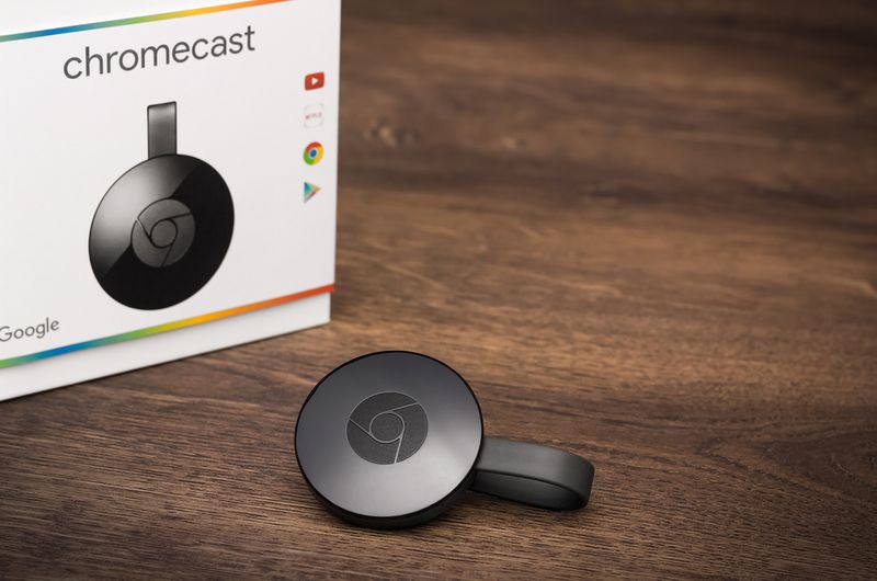 Google Chromecast on a wooden surface with its original box
