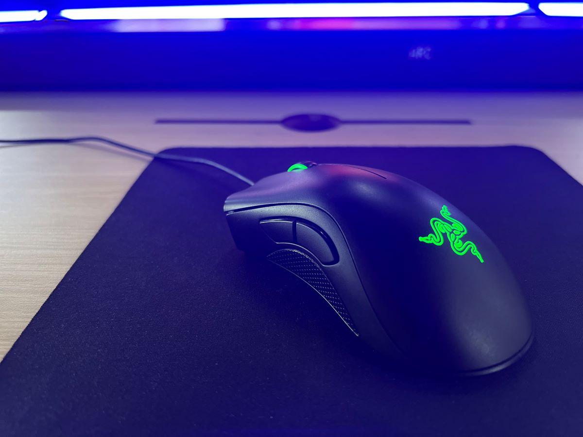 The Razer mouse on a table with a mouse pad under and a blue back light