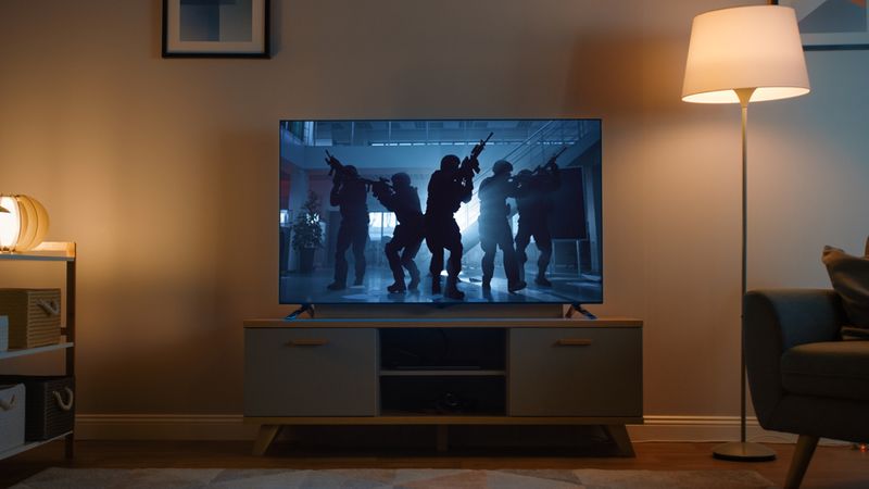 a TV in a dark living room with scene of action movie on the screen