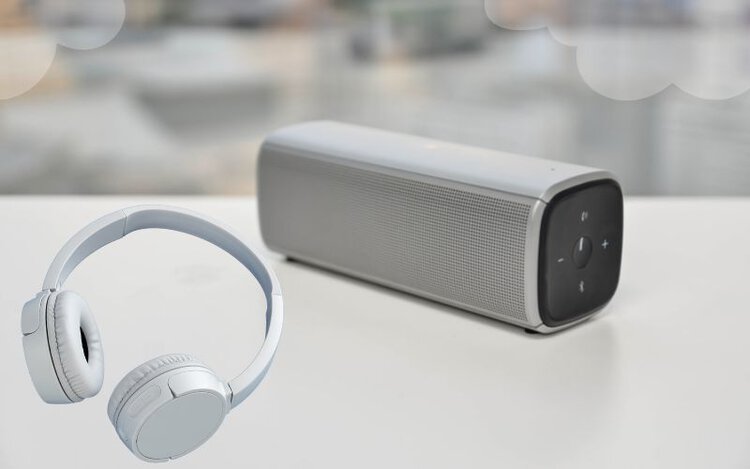 a bluetooth speaker and bluetooth headphone on the white table