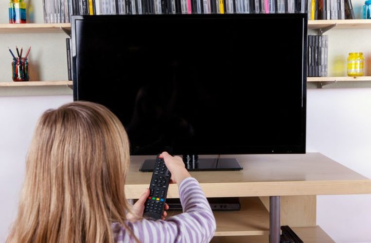 a child using remote to turn off TV in living room