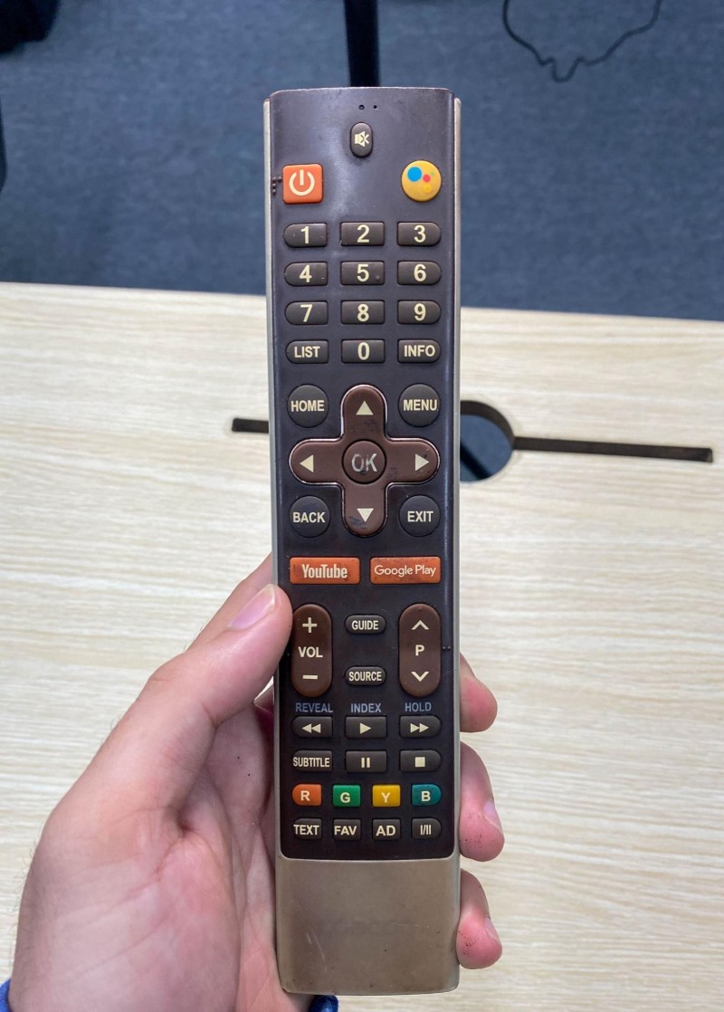 a hand is holding a Coocaa TV remote control