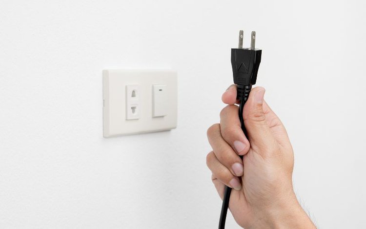 a hand unplugs the power cord of a device