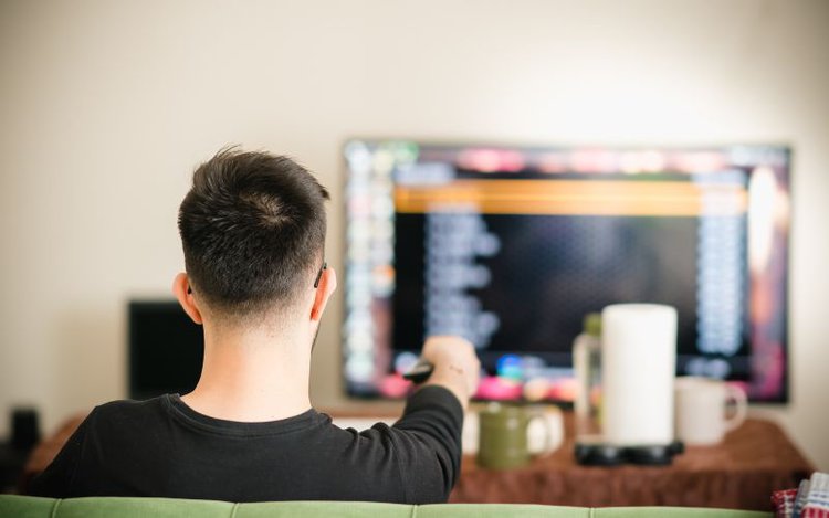 a man controls the TV with a remote