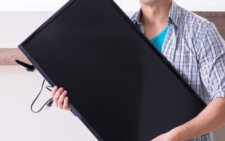 a man holding a TV in his arms
