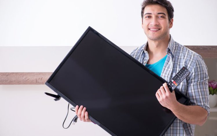 a man is carrying a TV alone