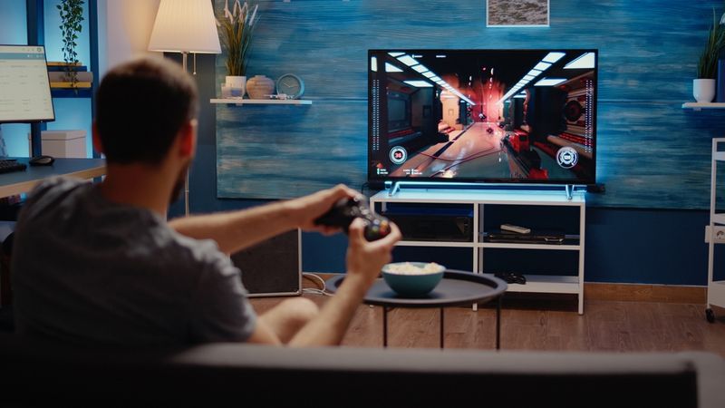 a man playing video game on TV at home