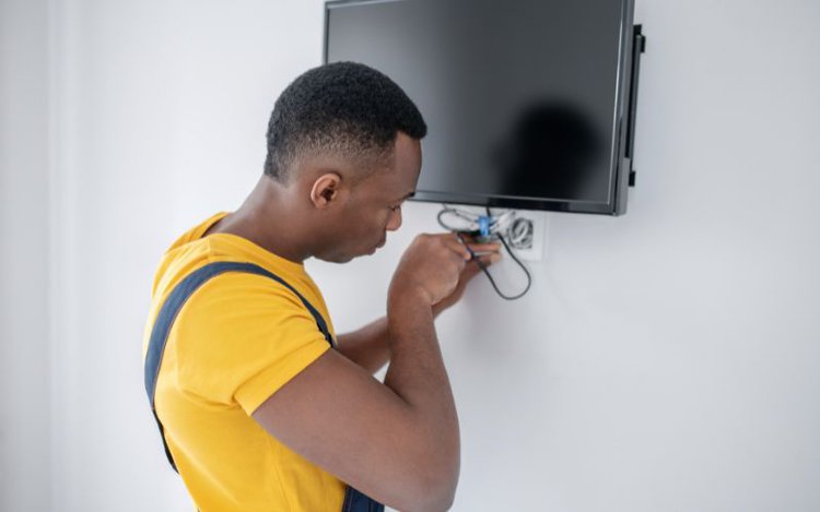 a service man fixes the wiring of a TV