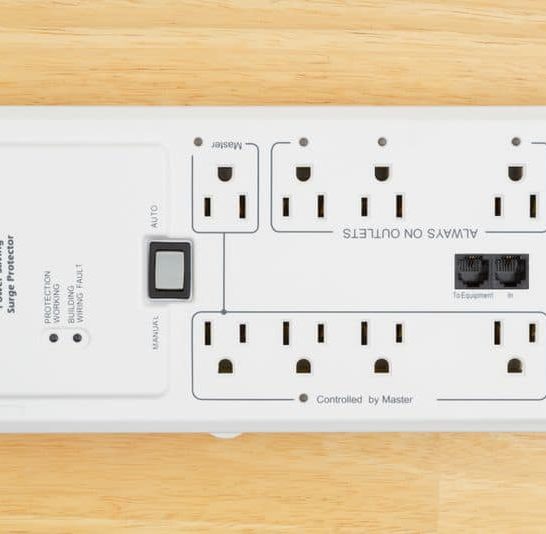 a white electrical power saving surge protector in wooden background