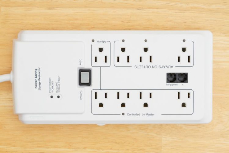 a white electrical power saving surge protector in wooden background