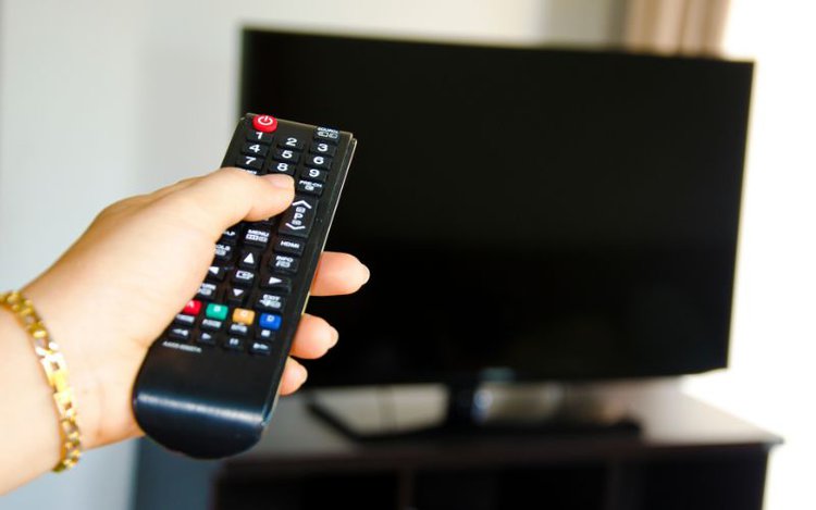hand using remote to turn off TV at home