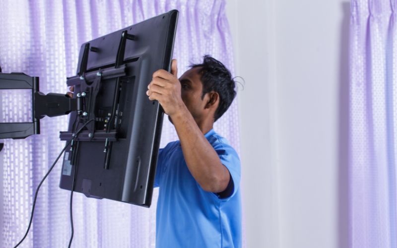 man adjusts the misaligned tv mount