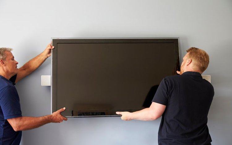 two people mount the TV to the wall