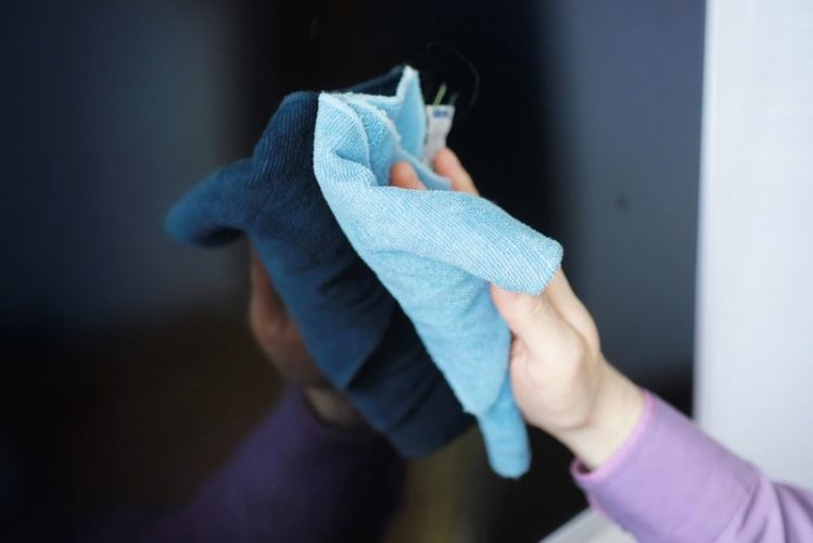 wiping dust on TV screen with a microfiber cloth