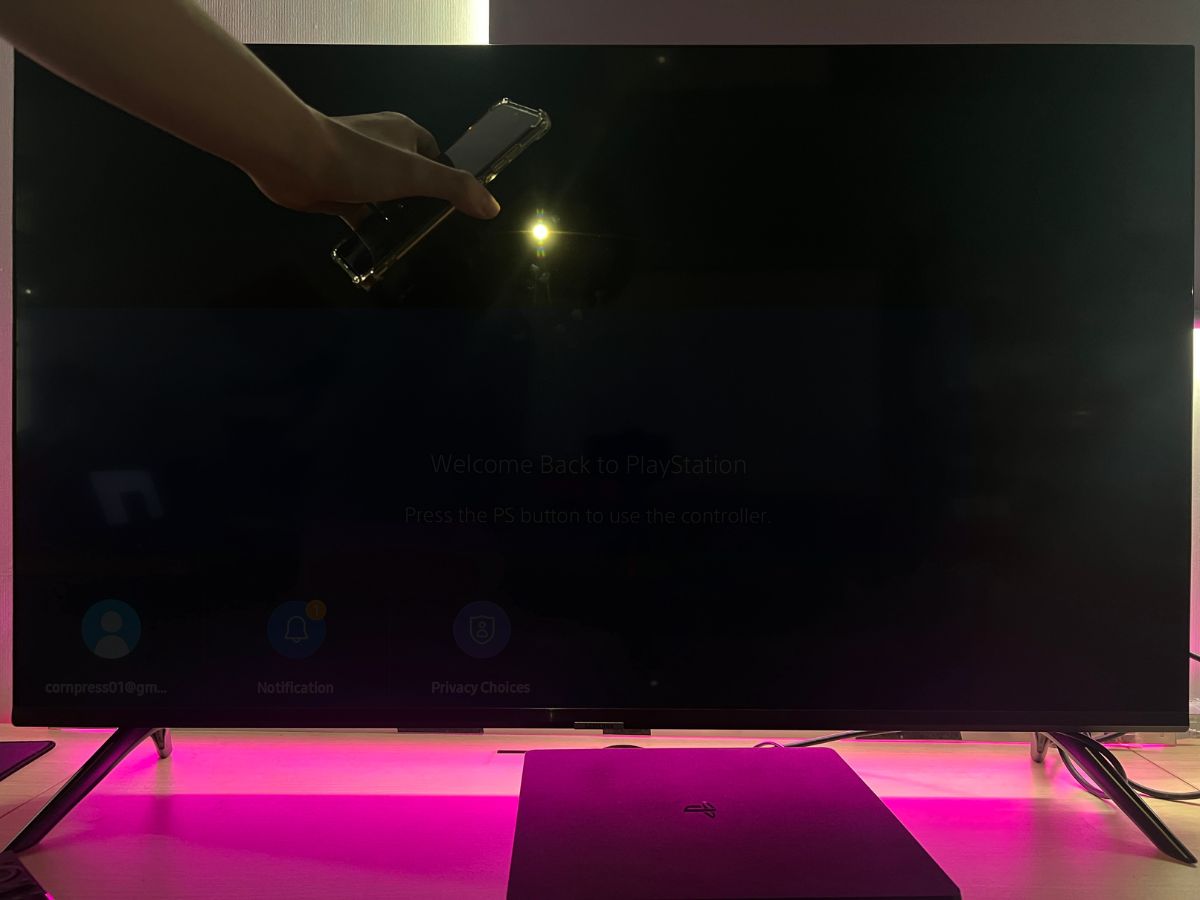 A hand is holding a phone while flashing light to the TV screen
