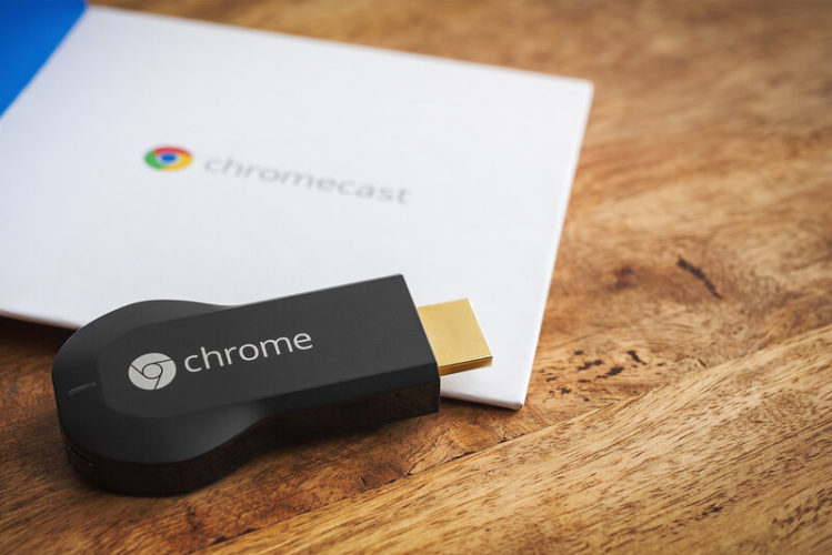 Um Chromecast de 1ª geração com sua caixa original na superfície de madeira