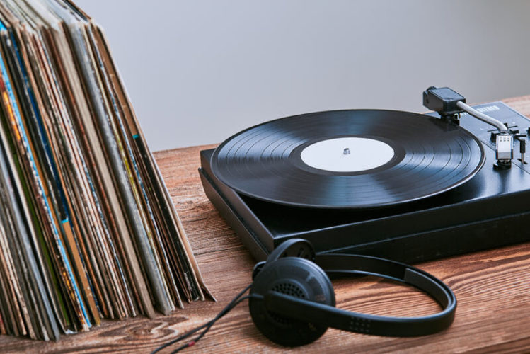 a black vinyl player with stack of vinyl record and headphone on the table