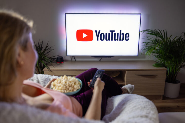 a woman sitting on a sofa and watching youtube on a tv