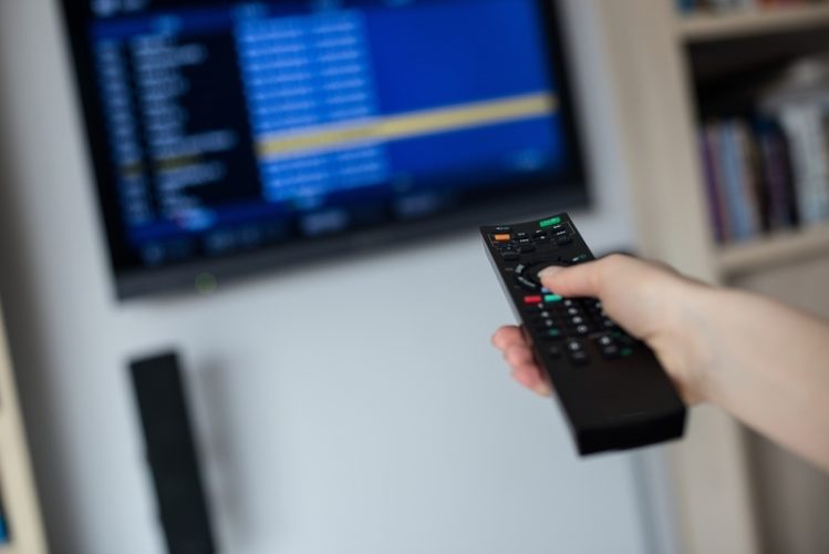 man holding remote to change TV resolutions