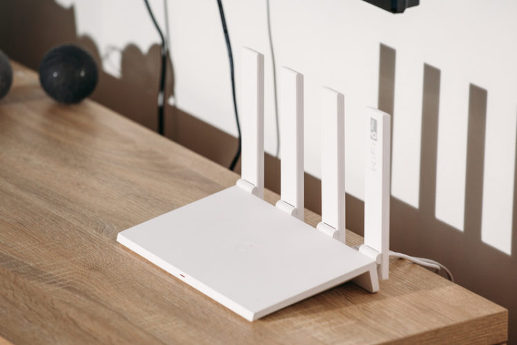 white wi-fi 6 router with 4 antennas on a wooden table