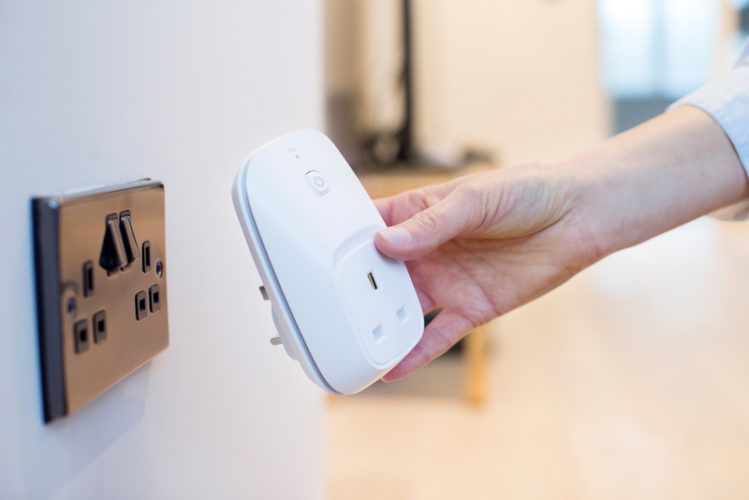 woman plugging smart plug into wall socket at home