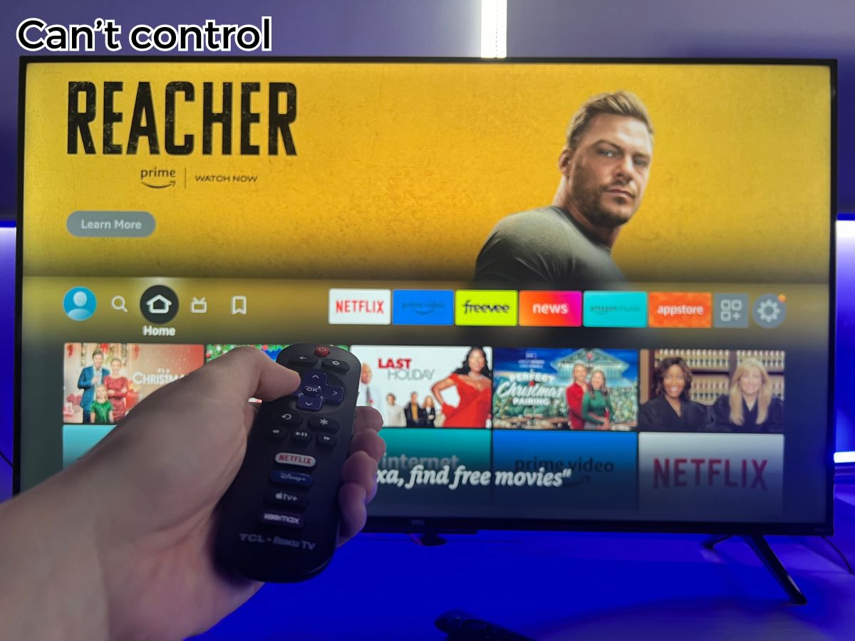 A hand is hold the Roku remote to control the Fire TV