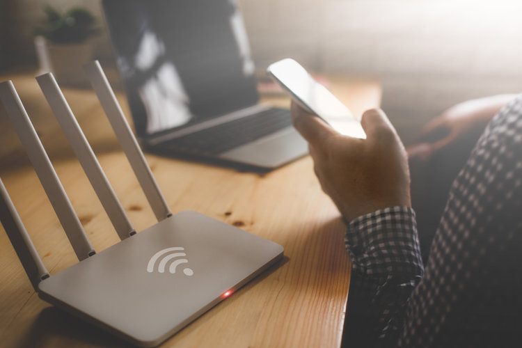 Wi -Fi 라우터 옆에 스마트 폰을 사용하는 남자