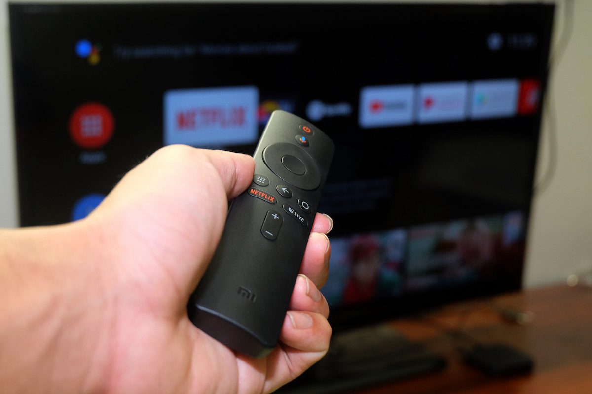 a man holds a remote pointing to a Mi TV