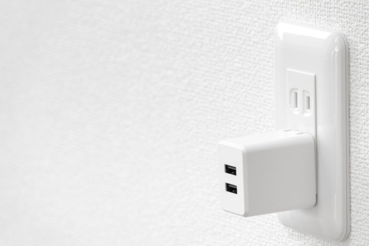 a white power adapter plugged in wall outlet