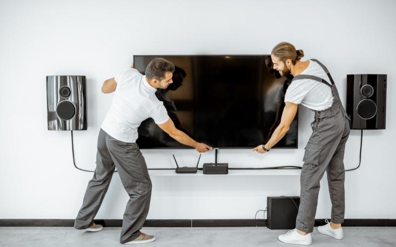 two men install a TV on the wall