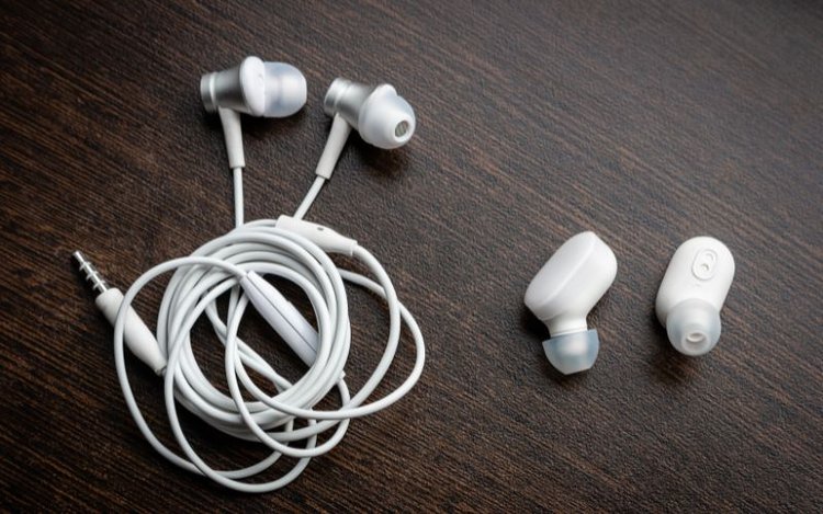 Weiße kabelgebundene Ohrhörer und weiße drahtlose Bluetooth-Kopfhörer