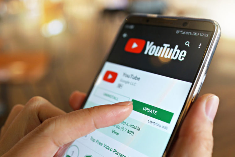 woman clicking update button of YouTube app on smartphone