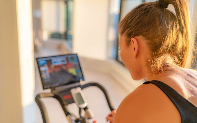 young girl watching the smart screen of her stationary bike during workout in her home