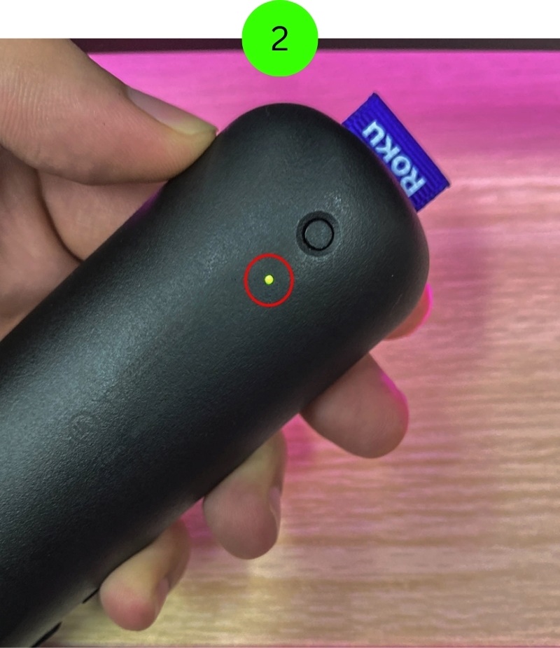 The LED indicator is flashing green on the Roku voice remote