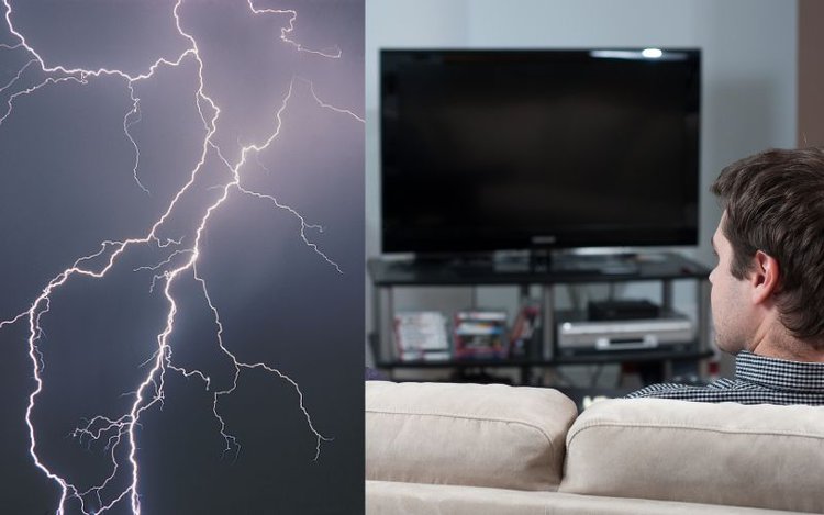 man is looking at TV with no signal after lightning