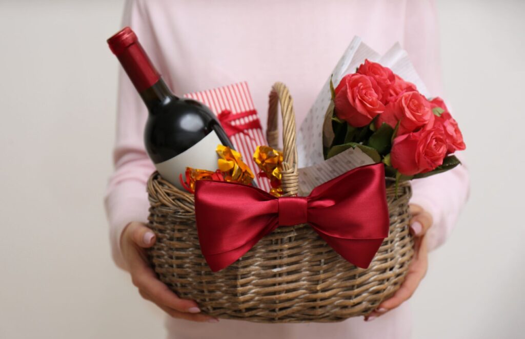 wicker basket with gift, bouquet and wine