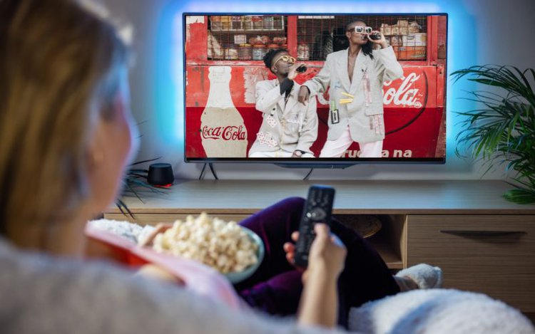 woman watching TV with coca cola ad on the screen