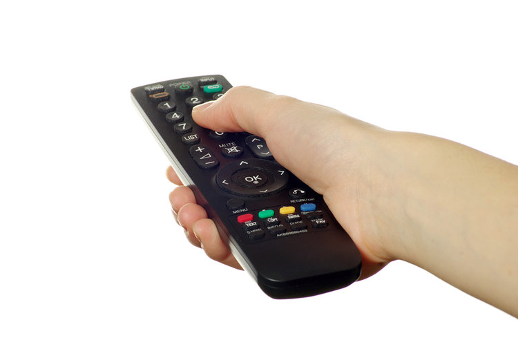 A hand holding a black universal remote