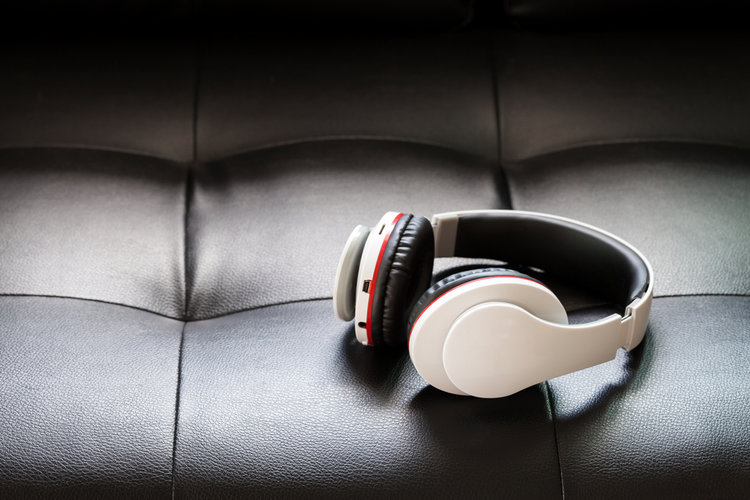 A white bluetooth headphones on a black couch